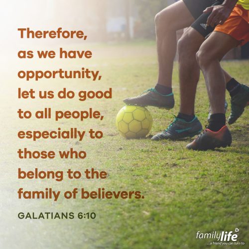 An excerpt of the daily verse to the left of the legs of soccer players fighting over a yellow ball