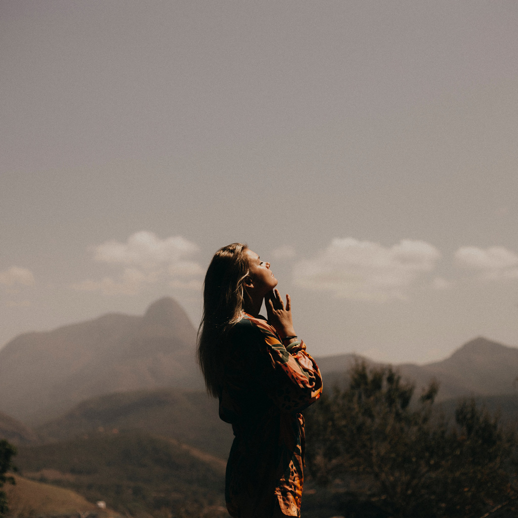 A woman in a mountain setting looking into late-noon sun